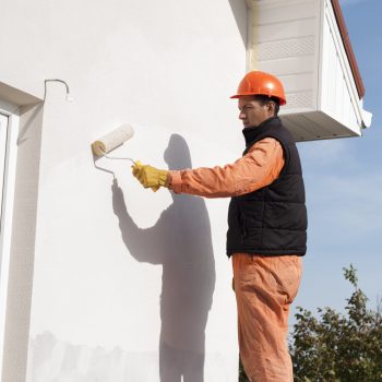 construction worker is painting a wall with a roller